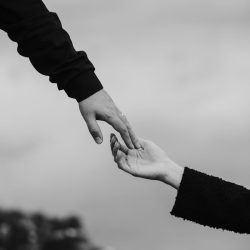 A touching black and white photograph capturing two hands reaching towards each other symbolizing connection.