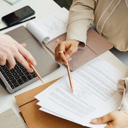 Office teamwork with two people reviewing documents and using a laptop